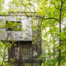 The tower house, © Robert Tober Modern tree house in a dense forest, surrounded by green leaves.