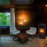 edelførst tree houses, © Robert Tober Interior view of a cozy tree house with two armchairs, a table and a wood-burning stove.