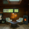 edelførst tree houses, © Robert Tober Interior view of a cozy tree house with wooden paneling, two armchairs, a table and a fireplace.