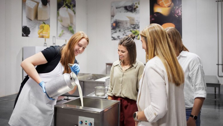 Show dairy, © Waldviertel Tourismus, Gerhard Wasserbauer A woman pours milk into a container while three people look on.
