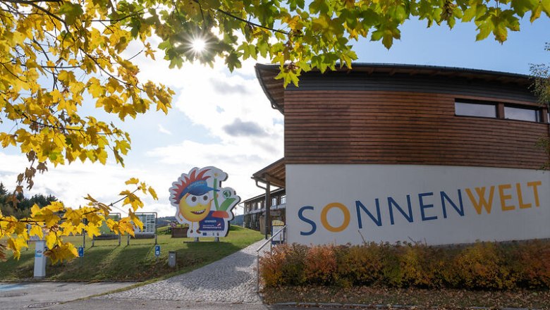 Außenansicht SONNENWELT Großschönau, © Waldviertel Tourismus, Claudia Schlager Eingang zur SONNENWELT Großschönau mit herbstlichen Bäumen und Sonnenschein.