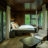 edelførst tree houses, © Robert Tober Interior view of a modern tree house with bed, armchairs and large windows with a view of the countryside.