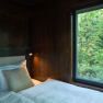 edelførst tree houses, © Robert Tober Interior view of a tree house with a bed and a window overlooking the forest.