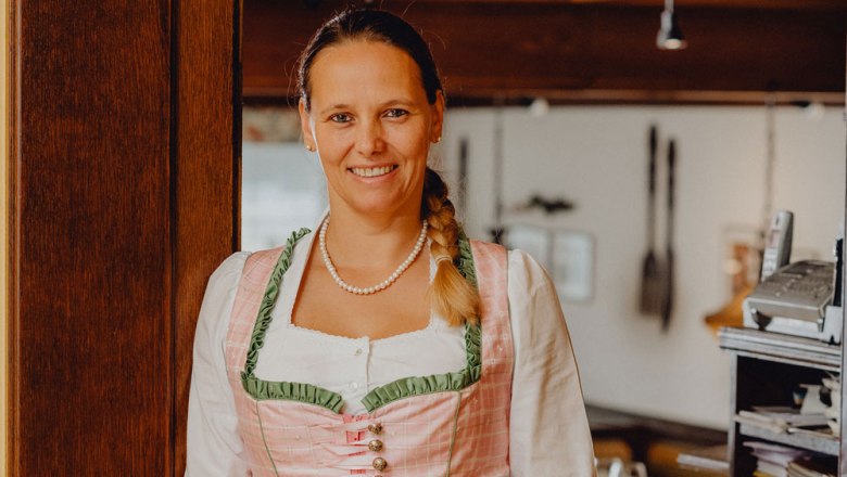 Im Service: Tamara Boigenzahn, © Niederösterreich Werbung/Klaus Engelmayer Frau in traditioneller Tracht lächelt in einem Restaurant.