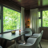 edelførst tree houses, © Robert Tober Interior view of a modern tree house with table, chairs and large windows with a view of the greenery.