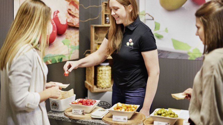 Tasting, © Waldviertel Tourismus, Gerhard Wasserbauer A woman offers two other women various stuffed peppers and olives to taste.