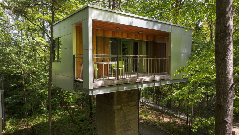 Modern tree house in the forest with balcony and glass front.