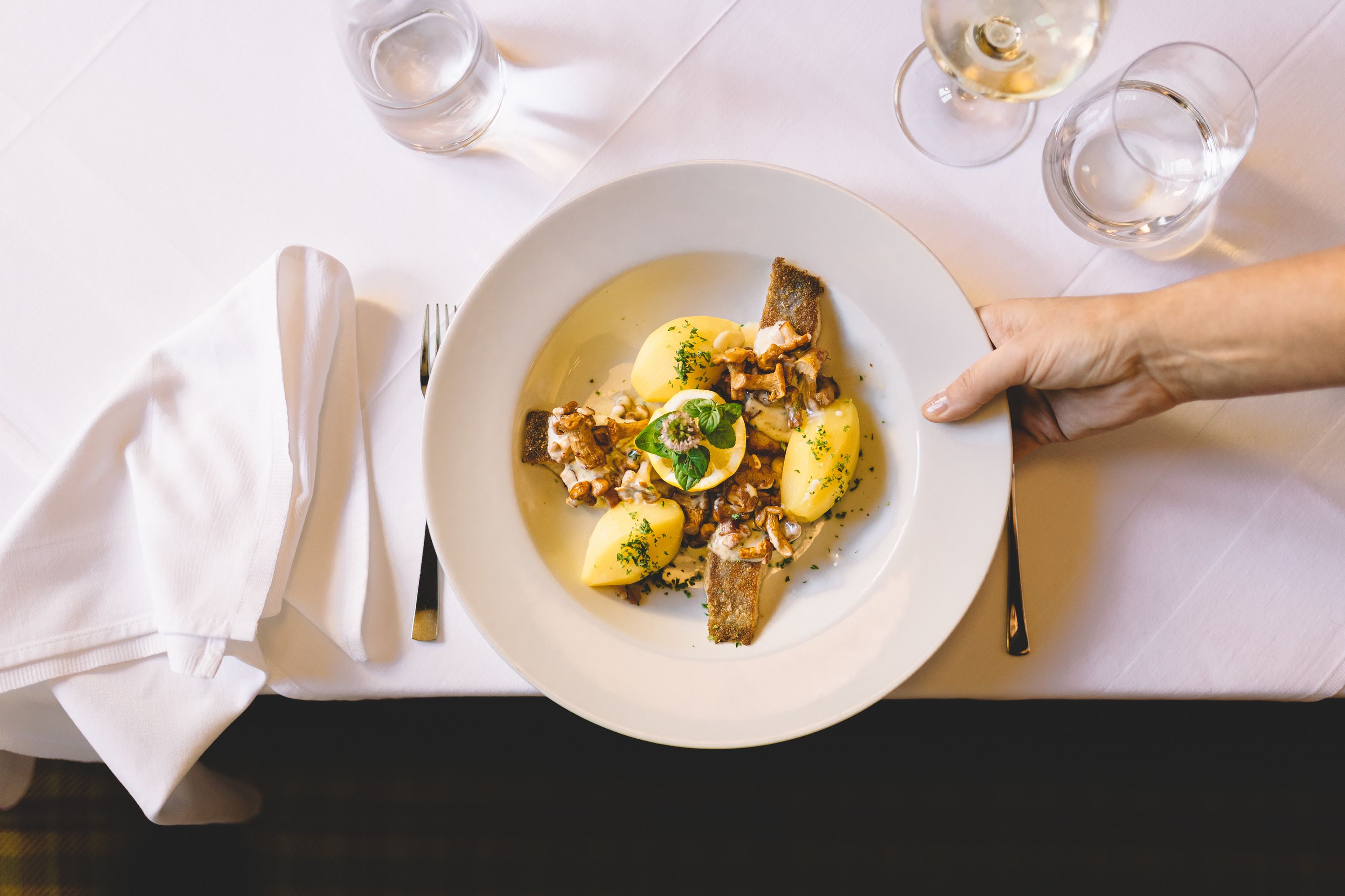 A plate of carp, potatoes and mushrooms on a white table.