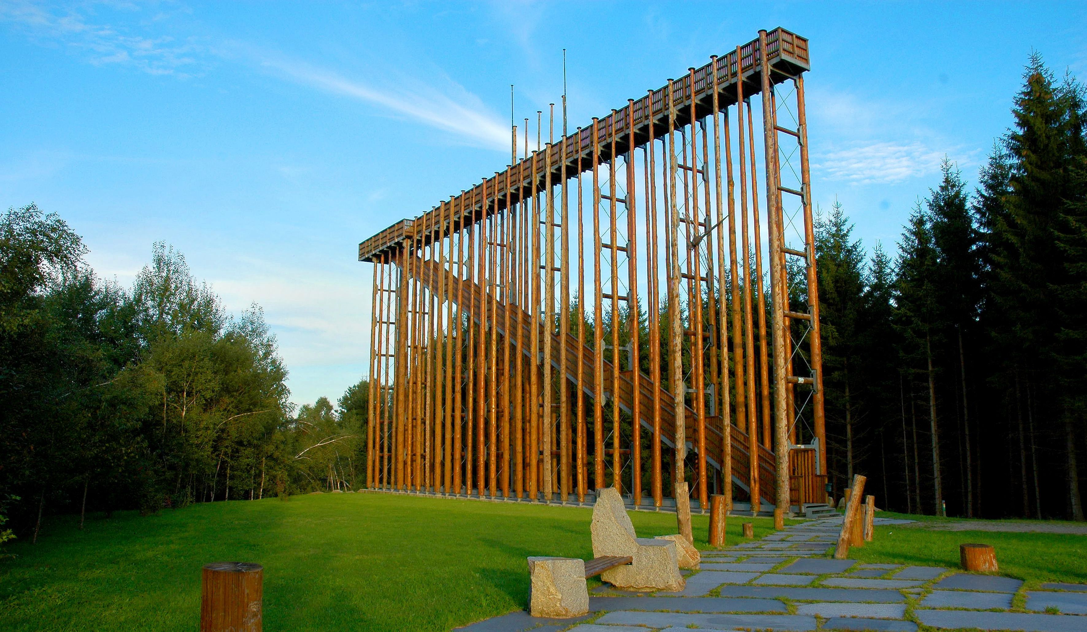 Eine hohe Holzkonstruktion im Freien, umgeben von Bäumen und grünem Gras.