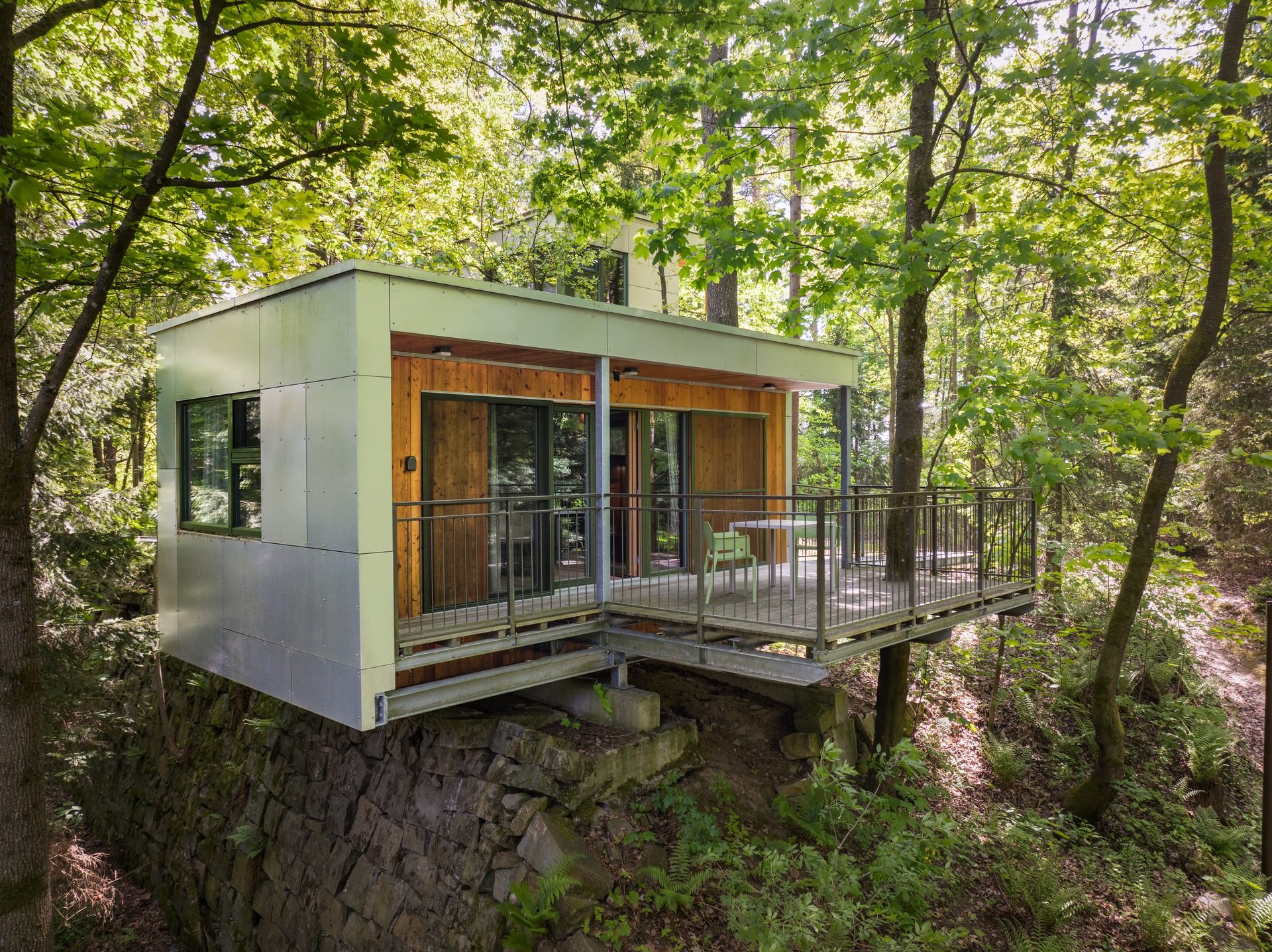 Modernes Baumhaus mit Terrasse im Wald.