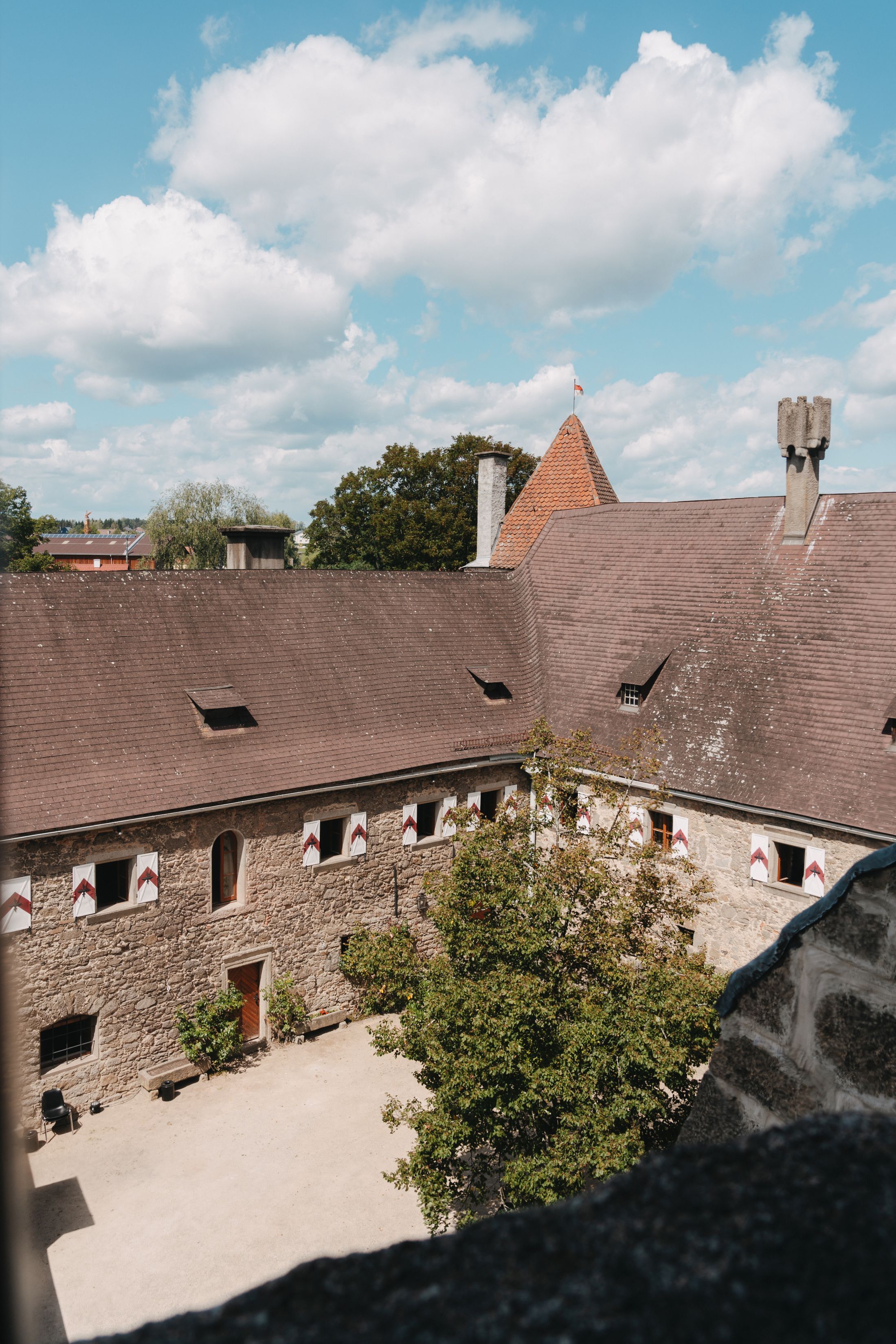 Innenhof der Burg Heidenreichstein mit Steinmauern und Ziegeldach unter blauem Himmel.