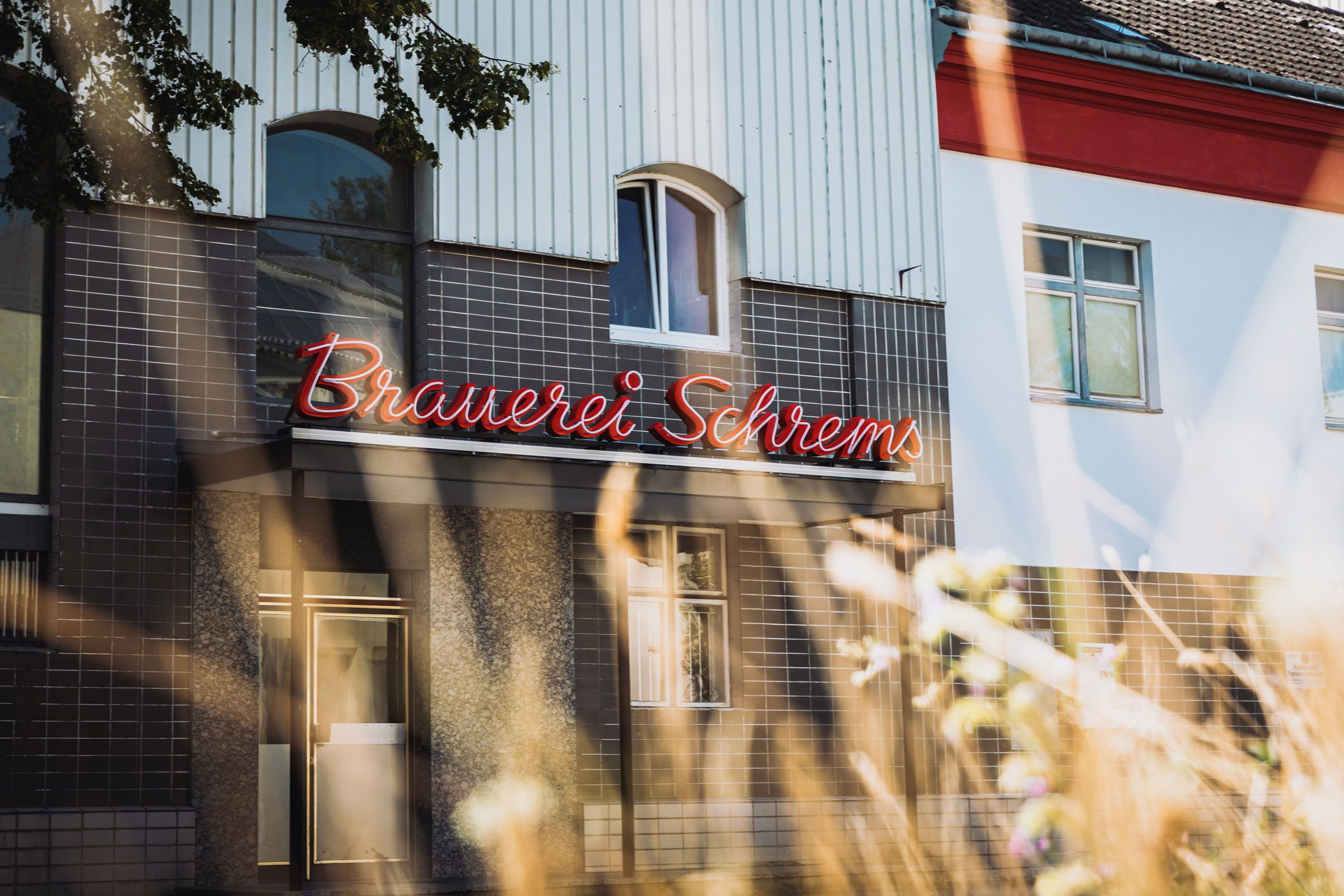 Fassade der Brauerei Schrems mit rotem Leuchtschild.