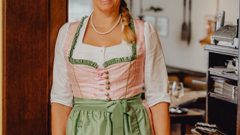 Woman in traditional costume smiling in a restaurant.