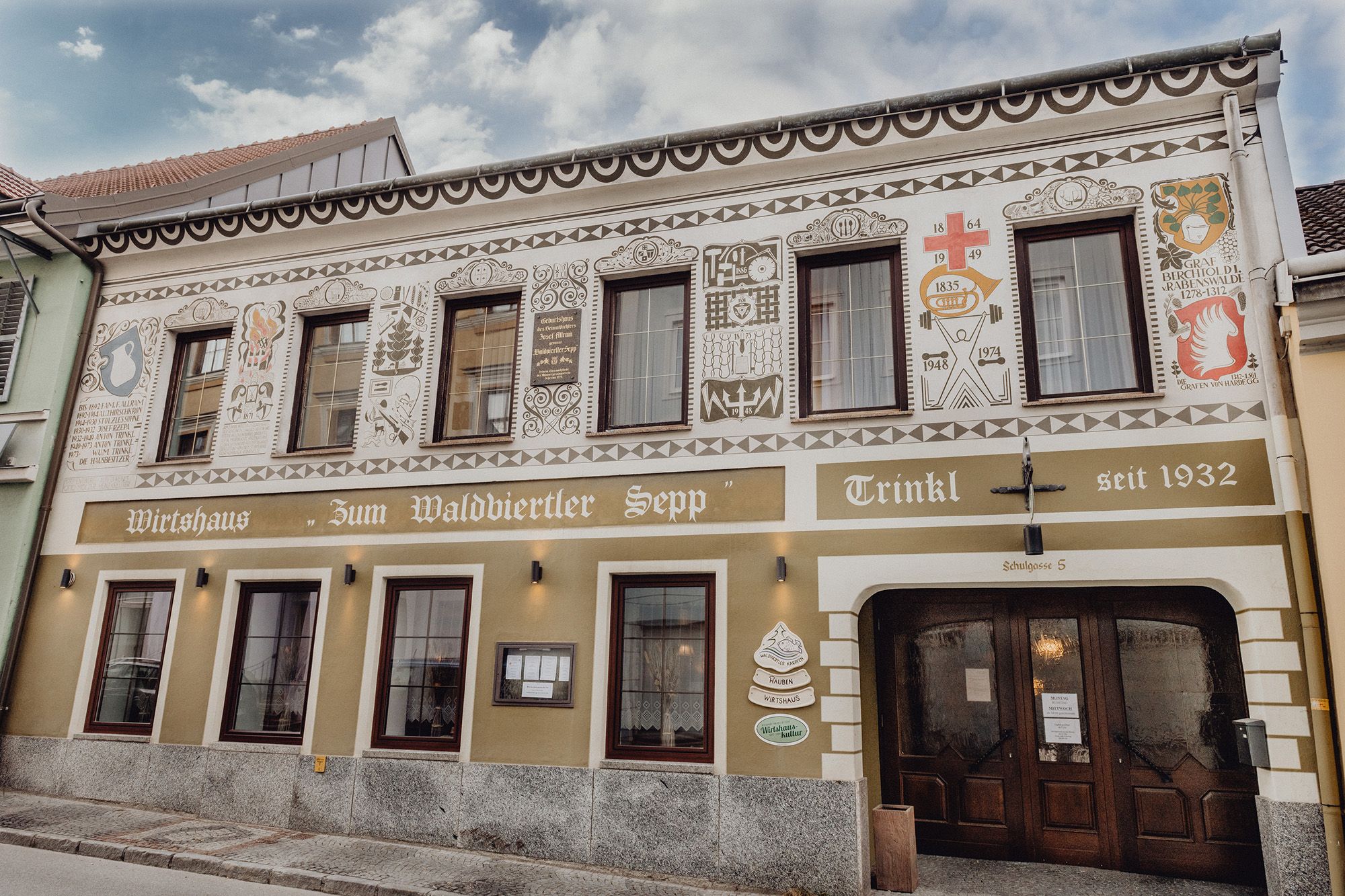 Fassade eines traditionellen Wirtshauses mit dekorativen Malereien und Schriftzug "Zum Waldviertler Sepp" in Schrems.